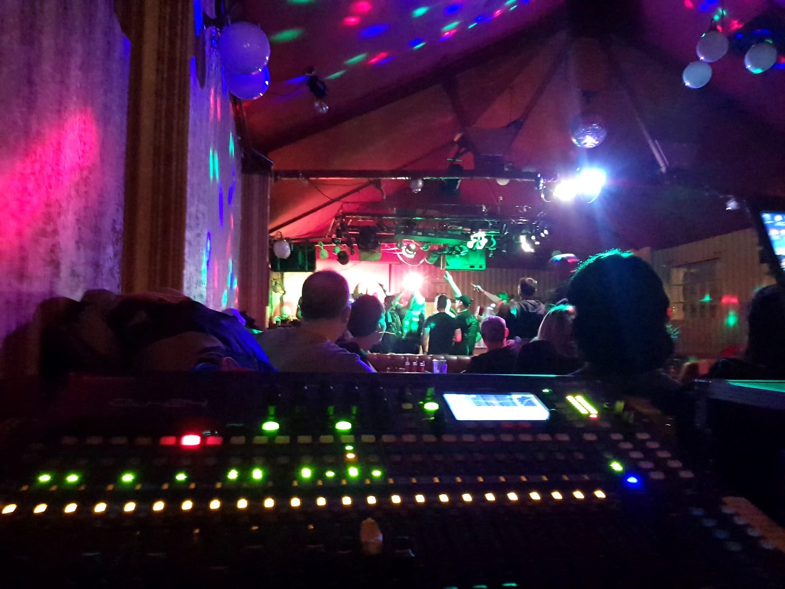 Front of house digital mixing desk at a live gig, with the band on stage and the crowd in front — SoundStar LIVE package