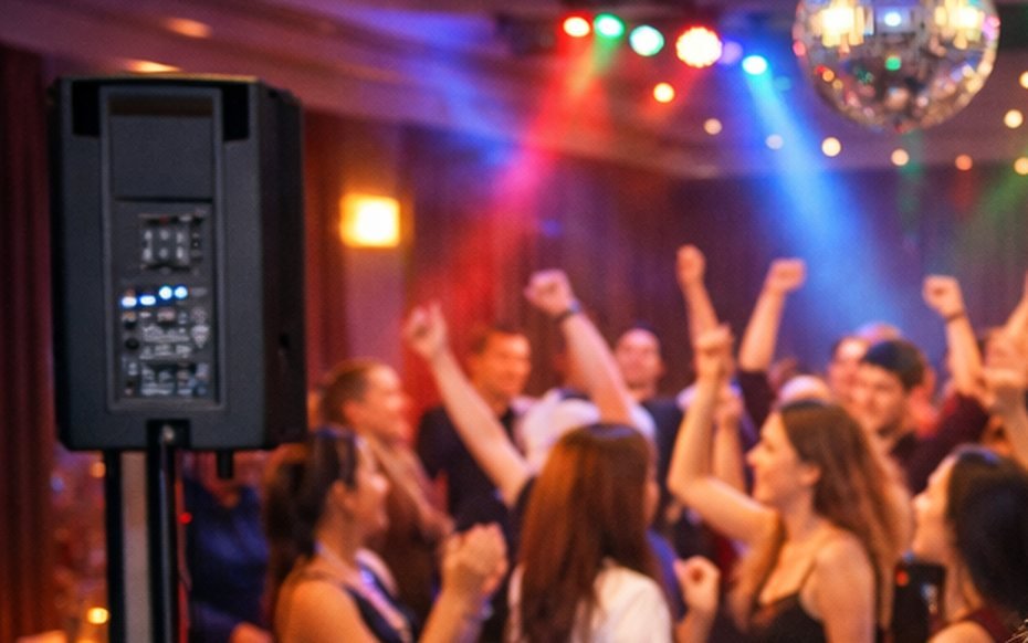 Active PA speaker on a stand beside a full dance floor under party lighting